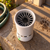 PackPaws dog paw washer on a sunlit stone step, open top showing the silicone fingers inside