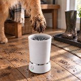 A muddy dog paw lowering into the PackPaws paw washer in a mudroom