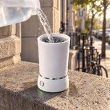 Water being poured into the PackPaws paw washer on an outdoor stone ledge